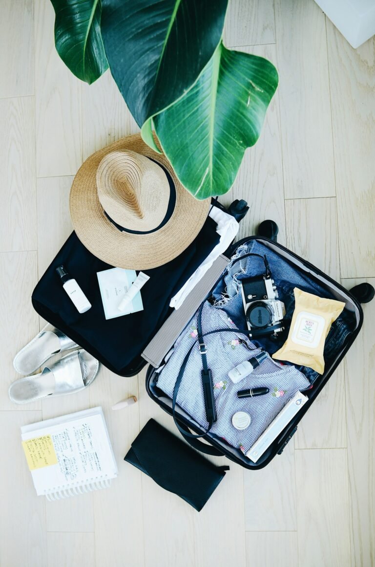 Open suitcase packed with travel essentials and a hat